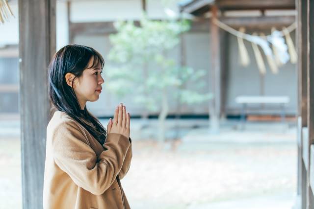 神社でお参りする女性