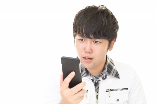 スマホを見て驚いている男性