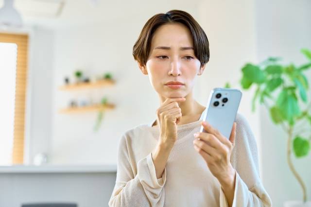 スマホを見て考える女性