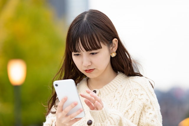 スマホ画面を見て不満に感じている女性