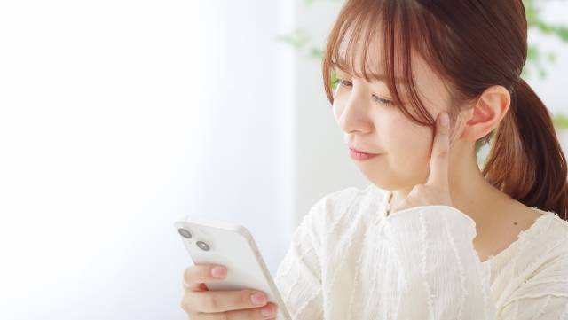 スマホを見て考える女性