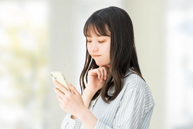 スマホを見て考える女性